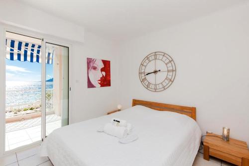 une chambre blanche avec une grande horloge sur le mur dans l'établissement Résidence Saint Rémy 2, à Cannes