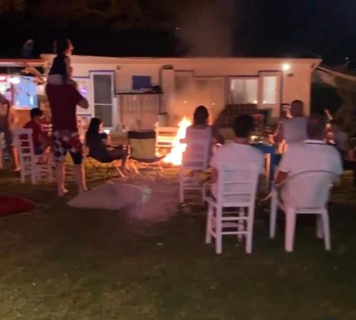 Bodrum Masali Camping في موغلا: مجموعة من الناس جالسين على كراسي أمام النار