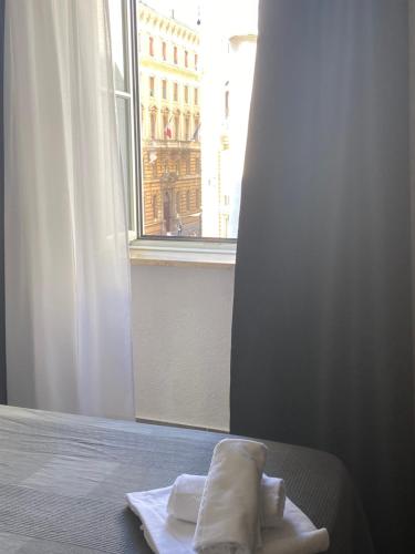 a bed with a white towel and a window at Hotel Centrale in Trieste
