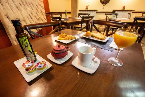 una mesa con un vaso de zumo de naranja y una taza de café en Los Canteros en Golmayo