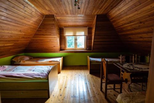 1 dormitorio con 2 camas y ventana en una casa de madera en Agroturystyka u Julii, en Helusz