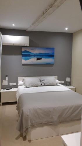 a bedroom with a white bed and a painting on the wall at Apartamentos Marques De La Merced in Málaga