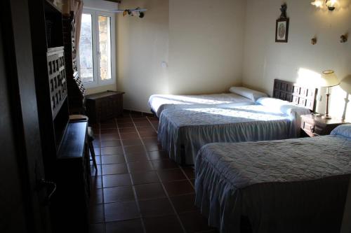 a hotel room with two beds and a television at Casa Rural Rincon de la Vega in Los Cortos