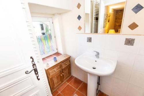 ein Bad mit einem Waschbecken, einem Spiegel und einem Fenster in der Unterkunft Mas Sarrat Apartment in Lherm