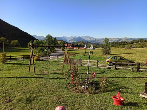 a field with a fence and a car in the background at Romantika in Šavnik