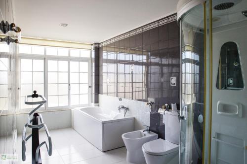 La salle de bains est pourvue d'une baignoire, de toilettes et d'un lavabo. dans l'établissement Help Yourself Hostels - Carcavelos Coast, à Carcavelos