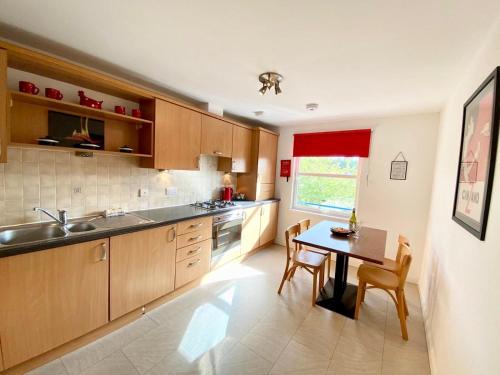 a kitchen with wooden cabinets and a table with chairs at Riverside Gardens Apartment in Inverness