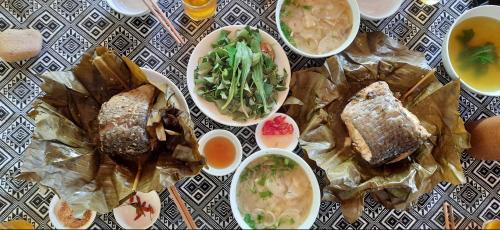 a table topped with bowls of soup and food at Mai Chau Xanh Bungalow in Mai Chau