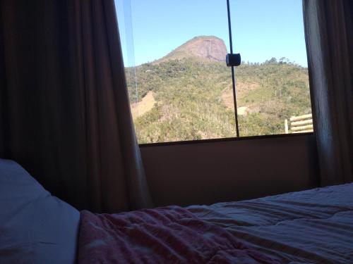 a bedroom window with a view of a mountain at Lumiar Chalé Jardim do Sossego in Lumiar