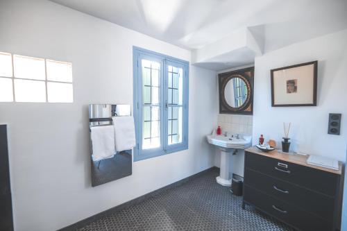 a white bathroom with a sink and a mirror at Villa Kumquats in Béziers