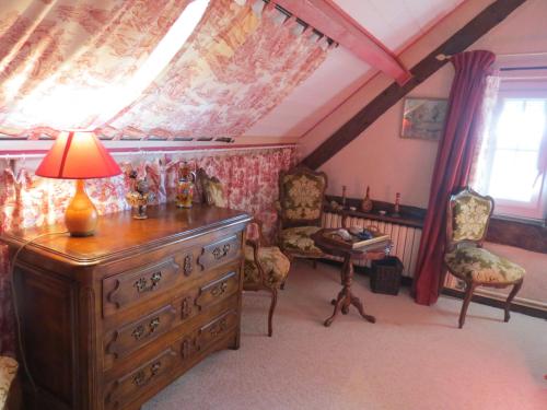 a room with a dresser with a lamp and chairs at Le Chant Des Fees in Notre-Dame-de-Courson