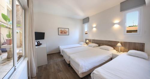a bedroom with three beds and a tv and a window at Centrum Hotel - City Center in Nicosia