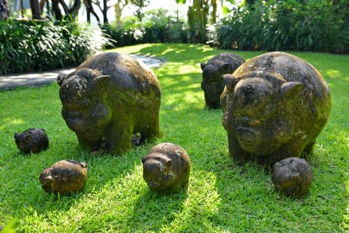 a statue of pigs sitting in the grass at The Damai in Lovina