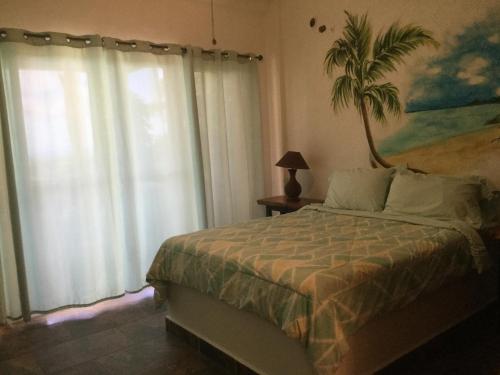 a bedroom with a bed and a palm tree mural at Hawk's Nest Bed & Breakfast in La Laguna de San Carlos