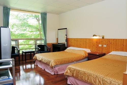 ein Hotelzimmer mit zwei Betten und einem Fenster in der Unterkunft 千禧山莊民宿 in Fengbin