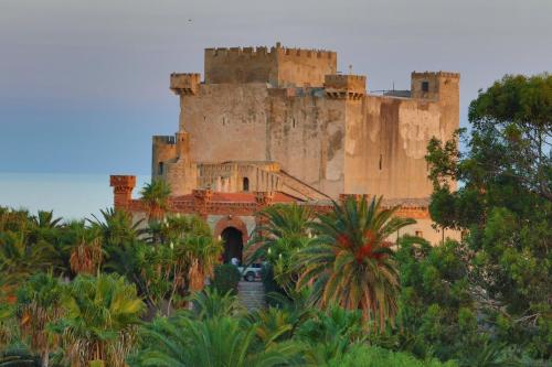 un castillo en la cima de una colina con palmeras en B&B Villa Sara Falconara, en Licata