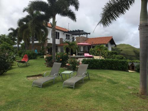 a house with two chairs and a table in the yard at Hawk's Nest Bed & Breakfast in La Laguna de San Carlos