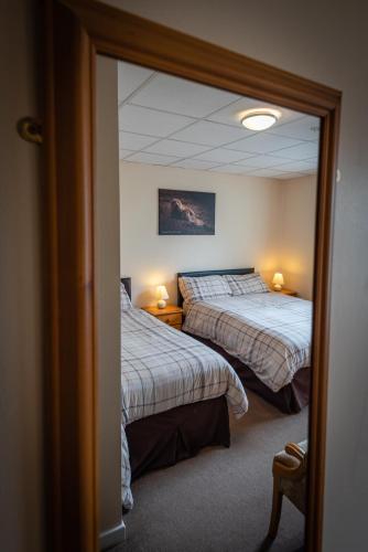 a reflection of a bedroom with two beds and a mirror at Aarondale Guest House in Hartlepool