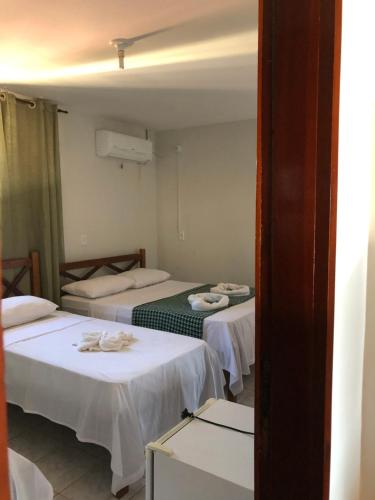 a room with two beds with white sheets at Pousada do Holandês in Canoa Quebrada