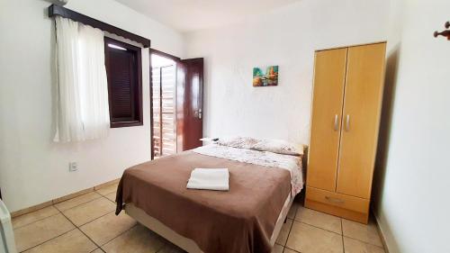 a small bedroom with a bed and a wooden cabinet at Hotel Praia Grande in Penha