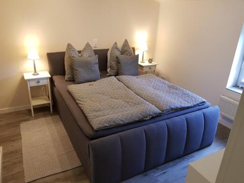 a large blue bed in a room with two lamps at Neu renovierte Ferienwohnung mit Poolhaus & Sauna auf dem Bauernhof in Oetzen