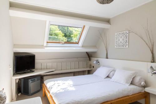 Schlafzimmer mit einem Bett, einem TV und einem Fenster in der Unterkunft Hotelroom Villa 1913 in Bergen