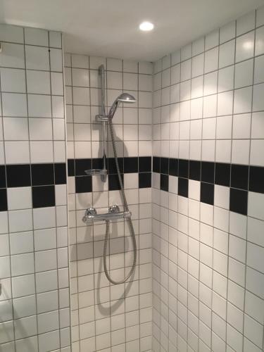 eine Dusche im Bad mit schwarzen und weißen Fliesen in der Unterkunft Hotelroom Villa 1913 in Bergen