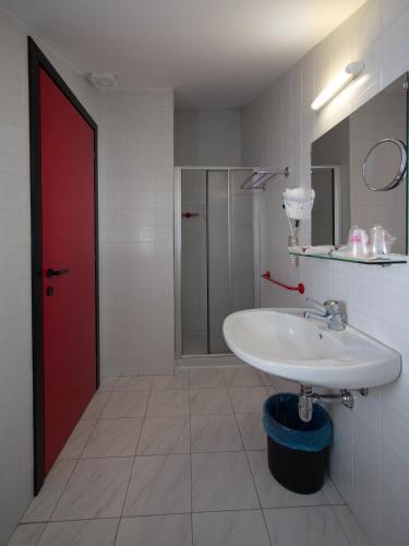 a bathroom with a white sink and a red door at Hotel Versailles in Colorno
