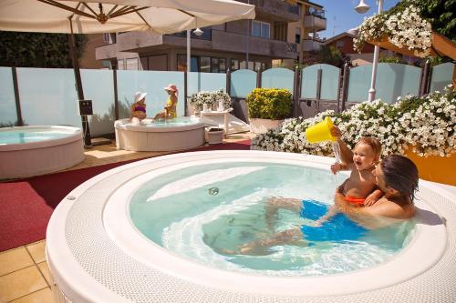 two children playing with a frisbee in a swimming pool at El Cid Campeador - Family Hotel in Rimini