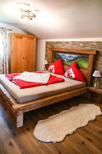 a bedroom with a large wooden bed with red pillows at Ferienhaus Schneiderhäusl Zillertal in Stummerberg