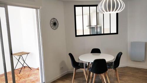 a dining room with a white table and black chairs at T2 55m2 Perpignan proche centre ville et gare avec parking in Perpignan