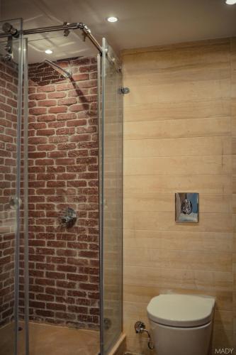 a bathroom with a toilet and a brick wall at Miramar Boutique Hotel in Alexandria