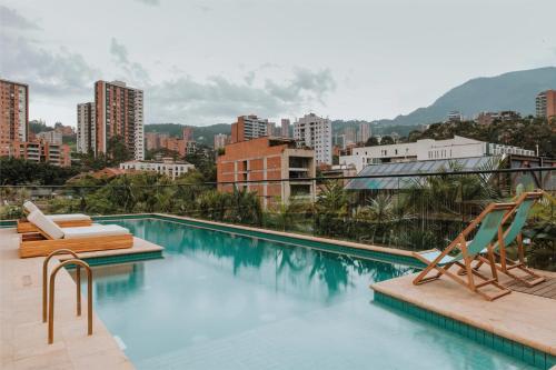 a swimming pool with two chairs and a city at The Click Clack Hotel Medellín in Medellín