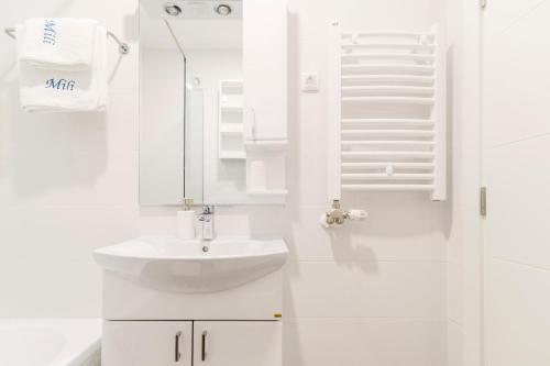een witte badkamer met een wastafel en een spiegel bij Mili Lux Apartman in Novi Sad