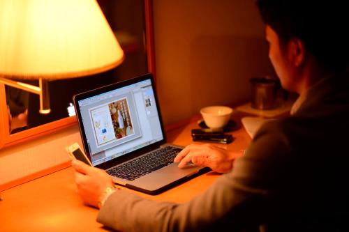 a woman sitting at a desk with a laptop computer at Hotel JAL City Aomori in Aomori