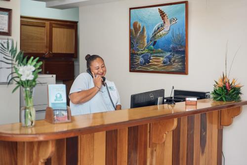 a woman talking on a phone at a reception desk at SunBreeze Suites in San Pedro