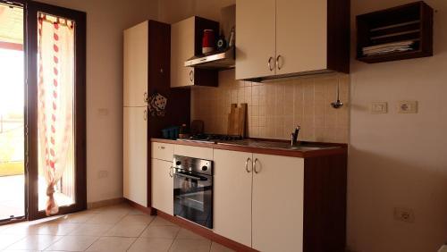 a kitchen with white cabinets and a stove top oven at Roccabianca in Sorso