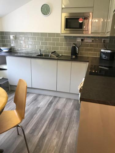 a kitchen with white cabinets and a microwave at Flat 1, 22 the square centre of Dalston village in Carlisle