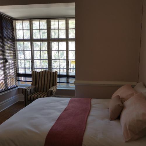 a bedroom with a bed and a chair and windows at Esperamos in Durban