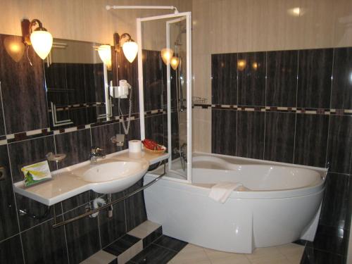 a bathroom with a tub and a sink and a bath tub at Atrium Hotel in Ivano-Frankivsʼk