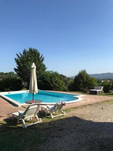 a swimming pool with two chairs and an umbrella at Il Casale di Lavinia in Fabro