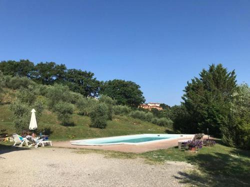 a swimming pool with a table and a umbrella at Il Casale di Lavinia in Fabro