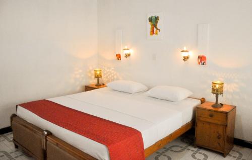 a bedroom with a bed with two night stands and two lamps at Hotel Thai Lanka in Hikkaduwa