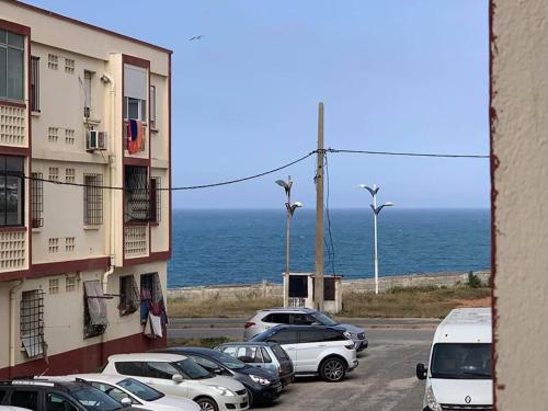 a parking lot with cars parked next to the ocean at Les Falaises in 'Aïn Taya