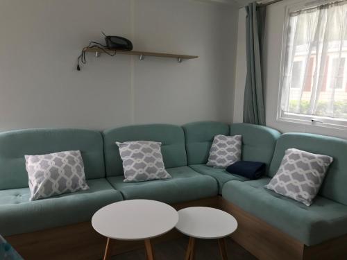 a living room with a green couch and two tables at CampingKer in Pont-Aven