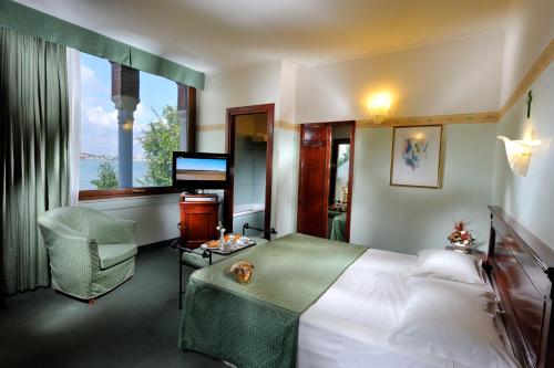 Habitación de hotel con cama y TV en Hotel Russo Palace, en Lido de Venecia