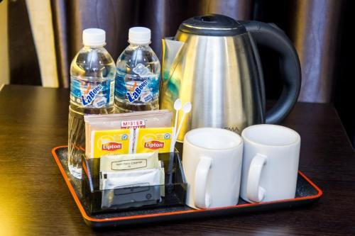 ein Tablett mit Tassen, einer Kaffeemaschine und Wasserflaschen in der Unterkunft Grand World Hotel in Johor Bahru