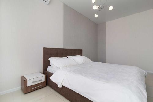 a white bedroom with a bed with a night stand at City Center 2-bedroom apartment in Dnipro