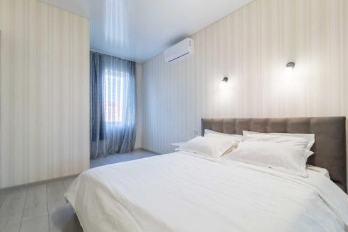 Un dormitorio con una gran cama blanca y una ventana en City Center 2-bedroom apartment, en Dnipro
