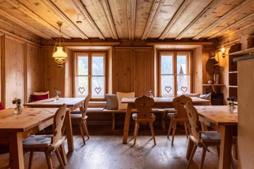 ein Esszimmer mit Holzwänden, Tischen und Fenstern in der Unterkunft Meisser Romantica "adults only" in Guarda